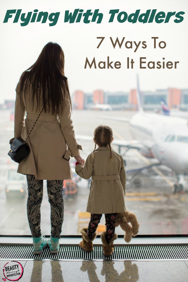 Mother and little daughter looking out the window at the airport terminal